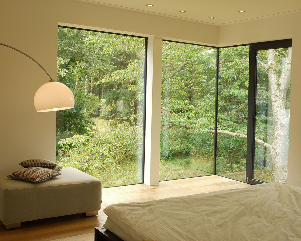 Photo of a contemporary bedroom in Nuremberg with white walls and light hardwood floors.