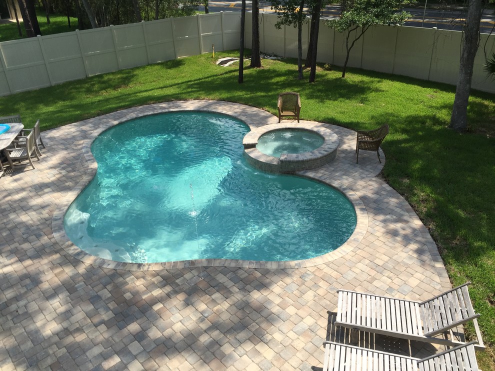 Design ideas for a mid-sized arts and crafts backyard custom-shaped pool in Jacksonville with a hot tub and brick pavers.
