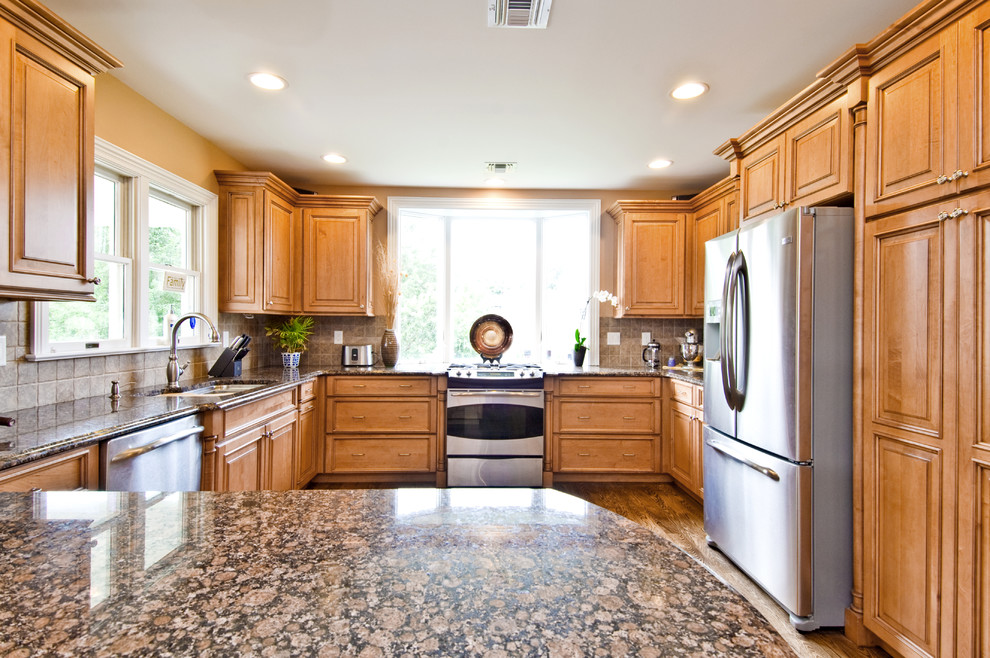 Kitchen - medium tone wood floor kitchen idea with a double-bowl sink, medium tone wood cabinets, granite countertops, beige backsplash and stainless steel appliances