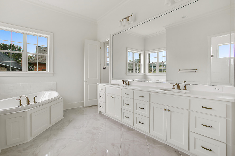Contemporary master bathroom in New Orleans with shaker cabinets, white cabinets, a drop-in tub, gray tile, porcelain tile, white walls, porcelain floors, an undermount sink and engineered quartz benchtops.