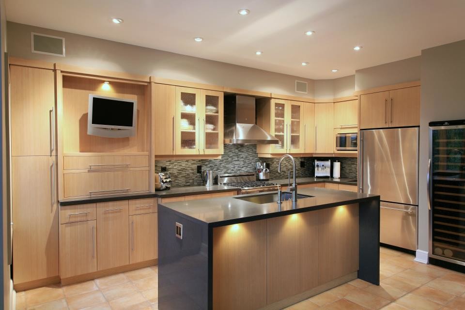 This is an example of a large transitional single-wall eat-in kitchen in Toronto with an undermount sink, raised-panel cabinets, light wood cabinets, quartz benchtops, metallic splashback, glass tile splashback, stainless steel appliances, dark hardwood floors, with island and brown floor.