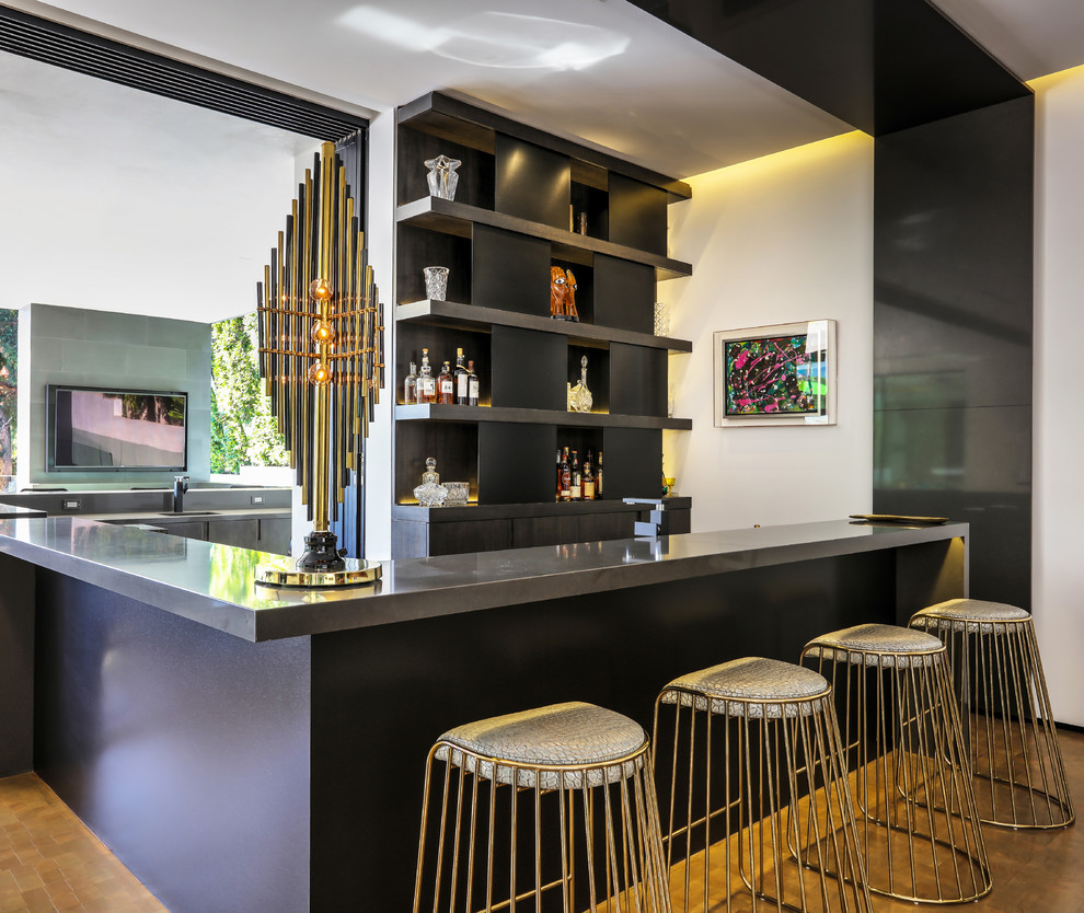 Contemporary u-shaped wet bar in Los Angeles with flat-panel cabinets, black cabinets, stainless steel benchtops, black splashback, medium hardwood floors, brown floor and grey benchtop.