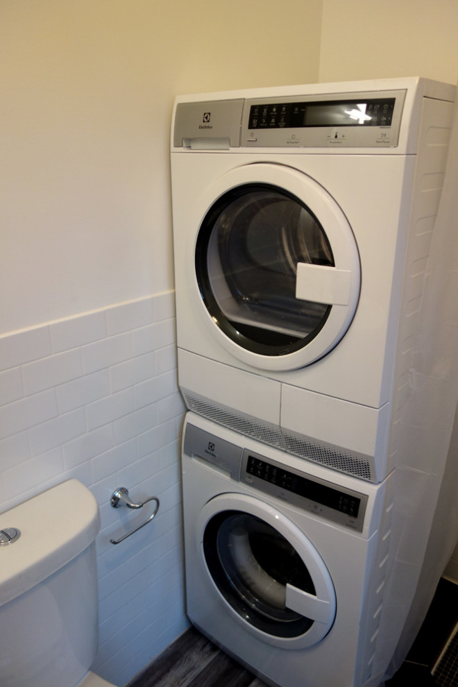 Idee per una piccola lavanderia multiuso classica con ante con bugna sagomata, ante bianche, pavimento in vinile, lavatrice e asciugatrice a colonna e pavimento grigio