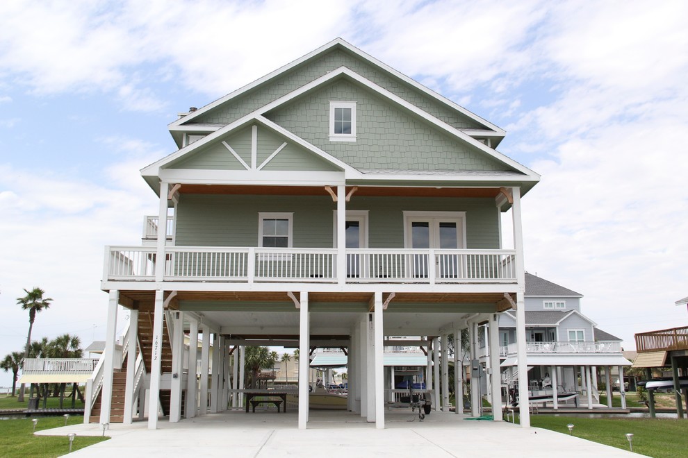 Large beach style two-storey green exterior in Houston with concrete fiberboard siding and a gable roof.