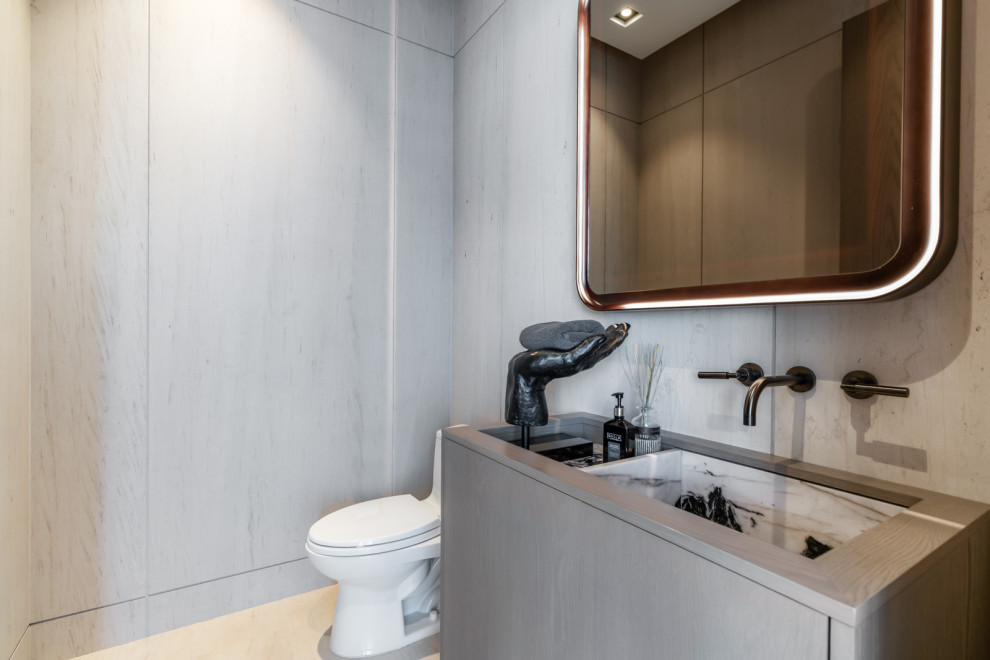 Photo of a contemporary bathroom in Miami with flat-panel cabinets, medium wood cabinets, a freestanding tub, a corner shower, a one-piece toilet, beige tile, limestone, limestone floors, marble benchtops, beige floor, a hinged shower door, white benchtops, a single vanity and a built-in vanity.