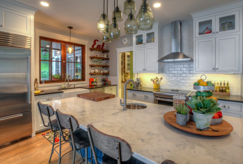 Kennedy Lake House - Open concept kitchen - mid-sized farmhouse l-shaped medium tone wood floor open concept kitchen idea in Grand Rapids with a farmhouse sink, shaker cabinets, white cabinets, quartzite countertops, white backsplash, stainless steel appliances and an island