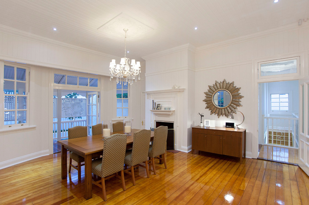 Large traditional separate dining room in Brisbane with white walls, light hardwood floors, a standard fireplace and a wood fireplace surround.