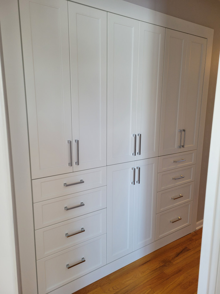 Diseño de armario y vestidor unisex moderno pequeño con a medida, armarios estilo shaker, puertas de armario blancas, suelo de madera clara y suelo marrón