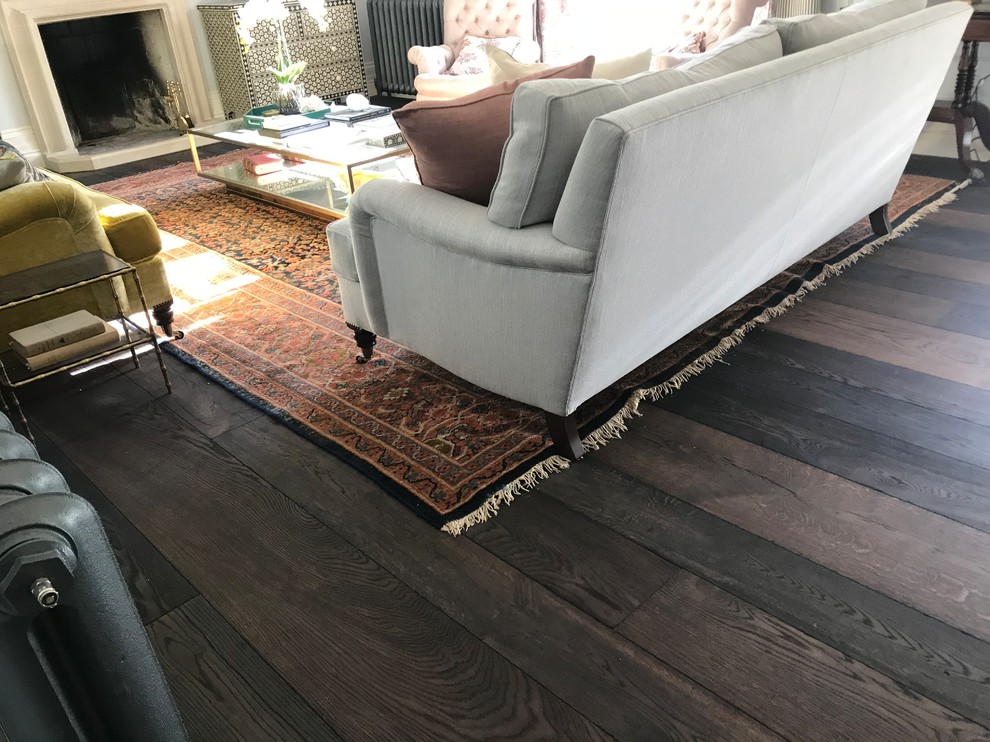 Inspiration for a large traditional enclosed living room in Sussex with white walls, dark hardwood flooring, a standard fireplace, a wooden fireplace surround and brown floors.