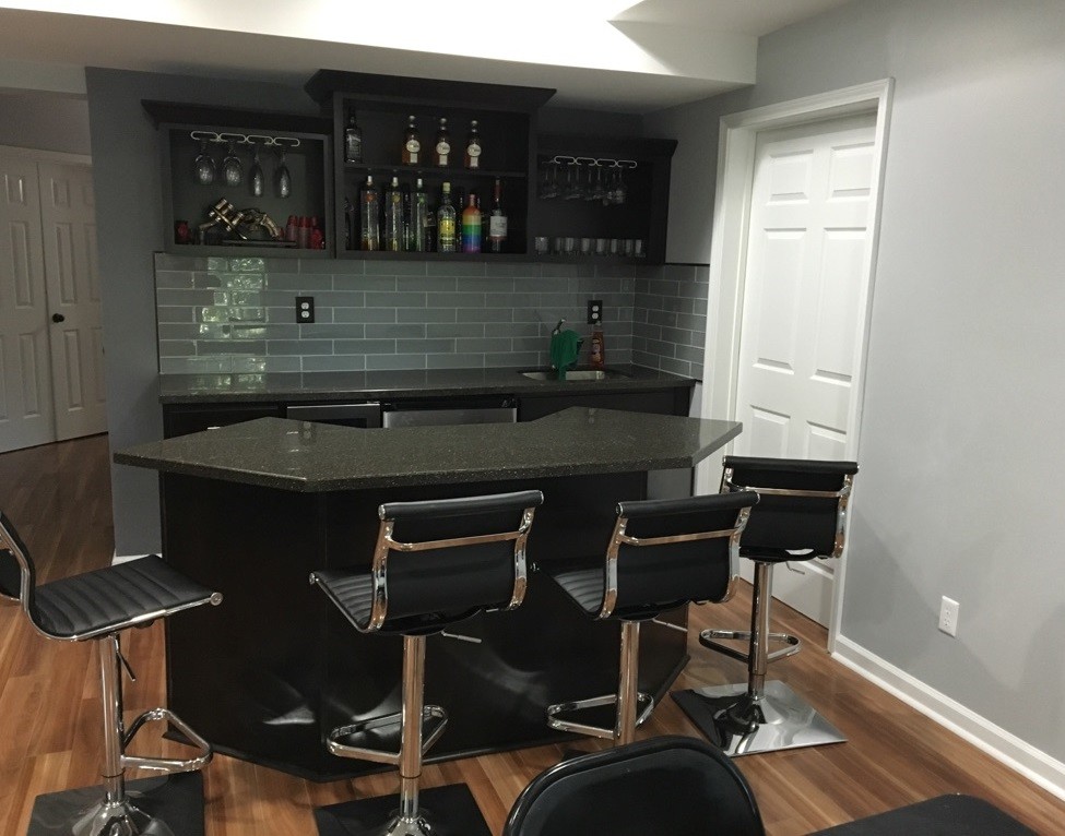 Photo of a small traditional galley wet bar in Atlanta with an undermount sink, shaker cabinets, dark wood cabinets, solid surface benchtops, grey splashback, glass tile splashback, laminate floors and beige floor.