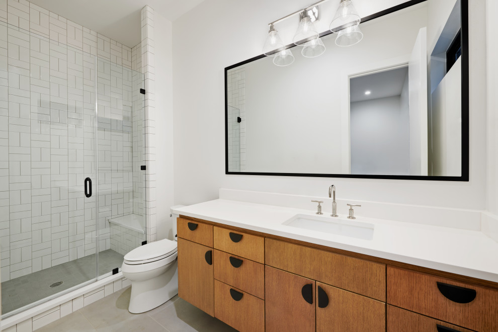 Mid-sized contemporary 3/4 bathroom in Austin with flat-panel cabinets, light wood cabinets, a curbless shower, white tile, subway tile, white walls, porcelain floors, an undermount sink, quartzite benchtops, grey floor, a hinged shower door and white benchtops.