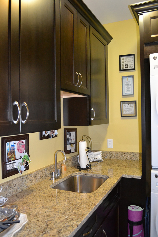 Example of a small transitional l-shaped home design design in Columbus with an undermount sink, recessed-panel cabinets, dark wood cabinets, granite countertops, yellow walls and a stacked washer/dryer