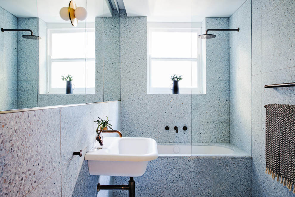 This is an example of a mid-sized contemporary master bathroom in Sydney with open cabinets, white cabinets, an undermount tub, a shower/bathtub combo, blue tile, blue walls, terrazzo floors, a wall-mount sink and blue floor.