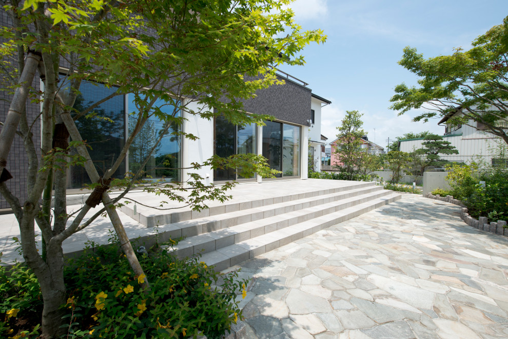 Inspiration for an expansive modern front patio in Other with natural stone paving.