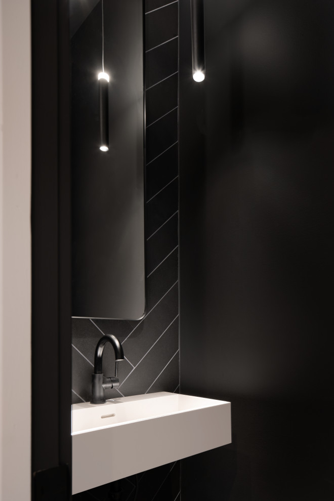 Foto di un piccolo bagno di servizio moderno con piastrelle nere, piastrelle in pietra, pareti nere, pavimento alla veneziana, lavabo sospeso e top bianco