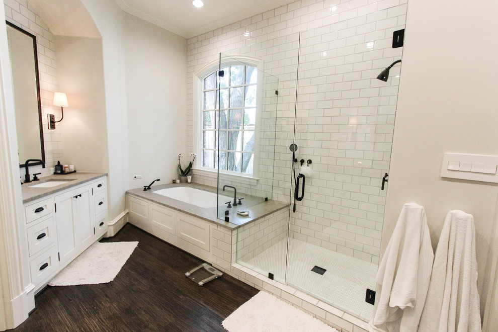 Design ideas for a mid-sized transitional master bathroom in Dallas with an undermount sink, white cabinets, soapstone benchtops, a drop-in tub, white tile, subway tile, white walls, dark hardwood floors, shaker cabinets, an alcove shower, brown floor and a hinged shower door.