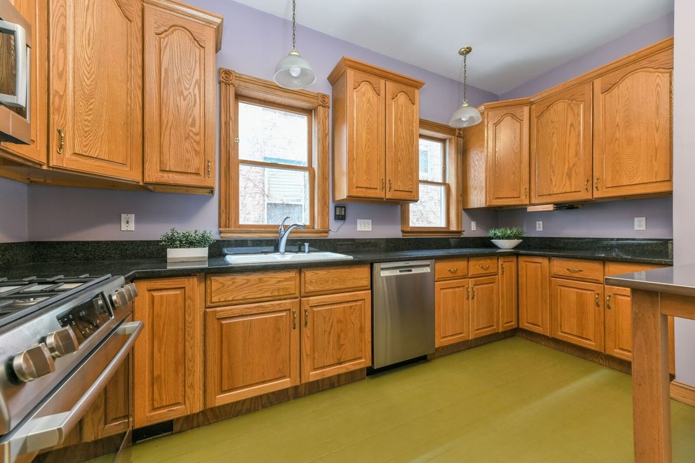 This is an example of a large traditional u-shaped separate kitchen in Boston with a drop-in sink, raised-panel cabinets, medium wood cabinets, granite benchtops, stainless steel appliances, no island, green floor and black benchtop.