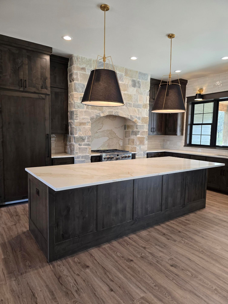 Example of a large transitional l-shaped vinyl floor and brown floor eat-in kitchen design with flat-panel cabinets, dark wood cabinets, quartz countertops, white backsplash, quartz backsplash, stainless steel appliances, an island and white countertops
