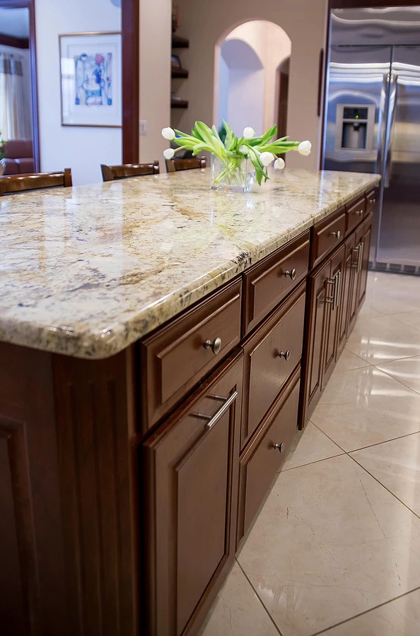 Example of a large minimalist u-shaped porcelain tile and beige floor open concept kitchen design with an undermount sink, raised-panel cabinets, dark wood cabinets, granite countertops, beige backsplash, matchstick tile backsplash, stainless steel appliances, an island and multicolored countertops