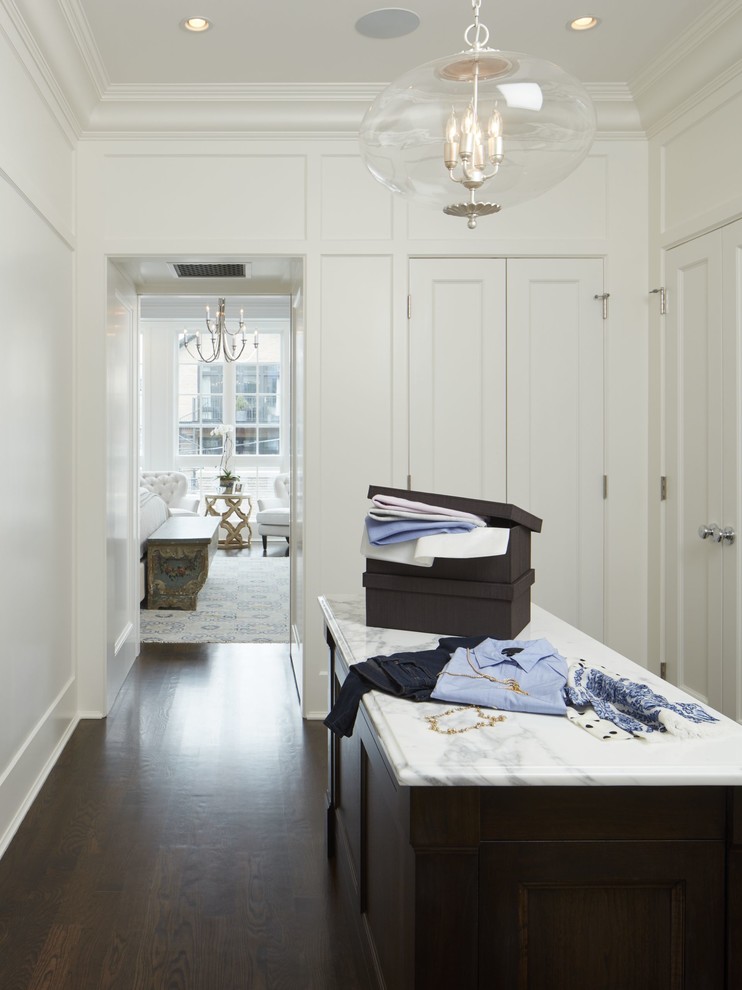 Design ideas for a large traditional gender-neutral storage and wardrobe in Chicago with dark hardwood floors, shaker cabinets, white cabinets and brown floor.