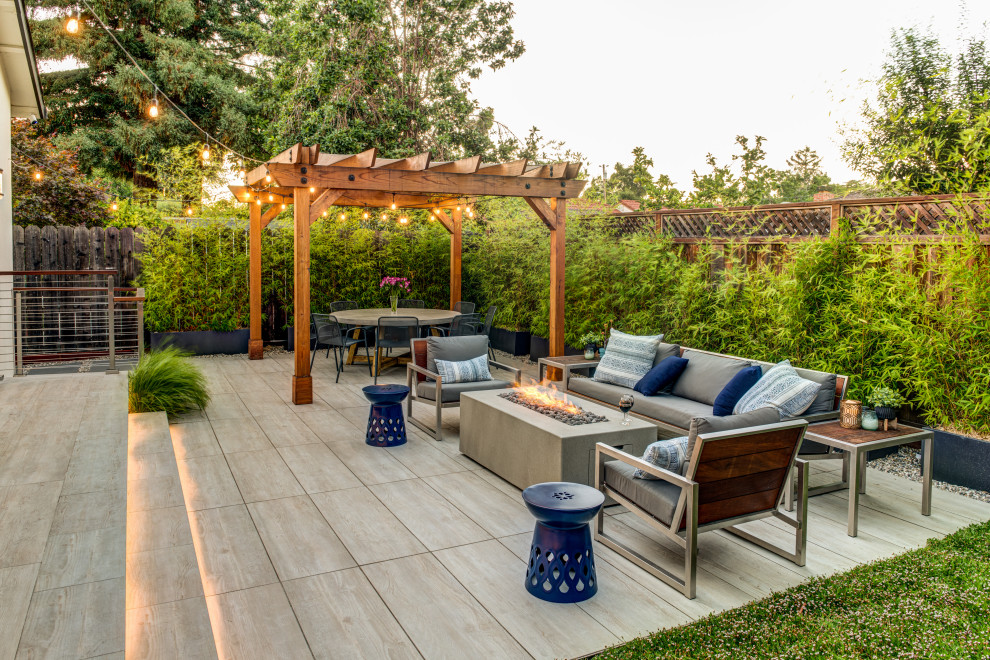 This is an example of a transitional patio in San Francisco with a fire feature, tile and a pergola.