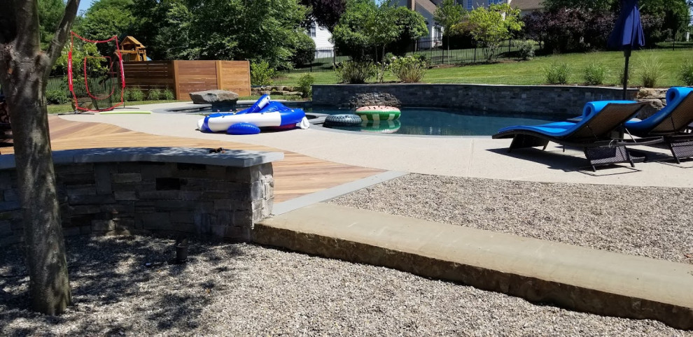 На фото: большой естественный ландшафтный бассейн в форме фасоли на заднем дворе в современном стиле с