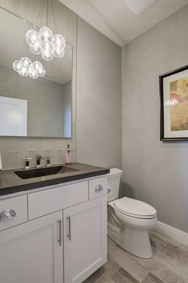 This is an example of a beach style powder room in Omaha with shaker cabinets, a two-piece toilet, an integrated sink and concrete benchtops.