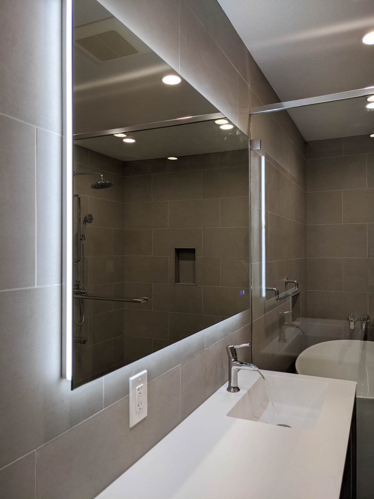 Large modern master wet room bathroom in San Francisco with flat-panel cabinets, brown cabinets, a freestanding tub, a two-piece toilet, gray tile, porcelain tile, grey walls, porcelain floors, a drop-in sink, solid surface benchtops, grey floor, a hinged shower door, white benchtops, a niche, a single vanity and a floating vanity.