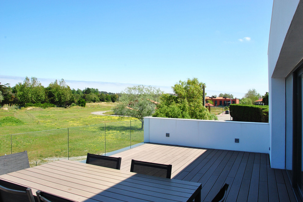 Modelo de terraza minimalista de tamaño medio con barandilla de vidrio