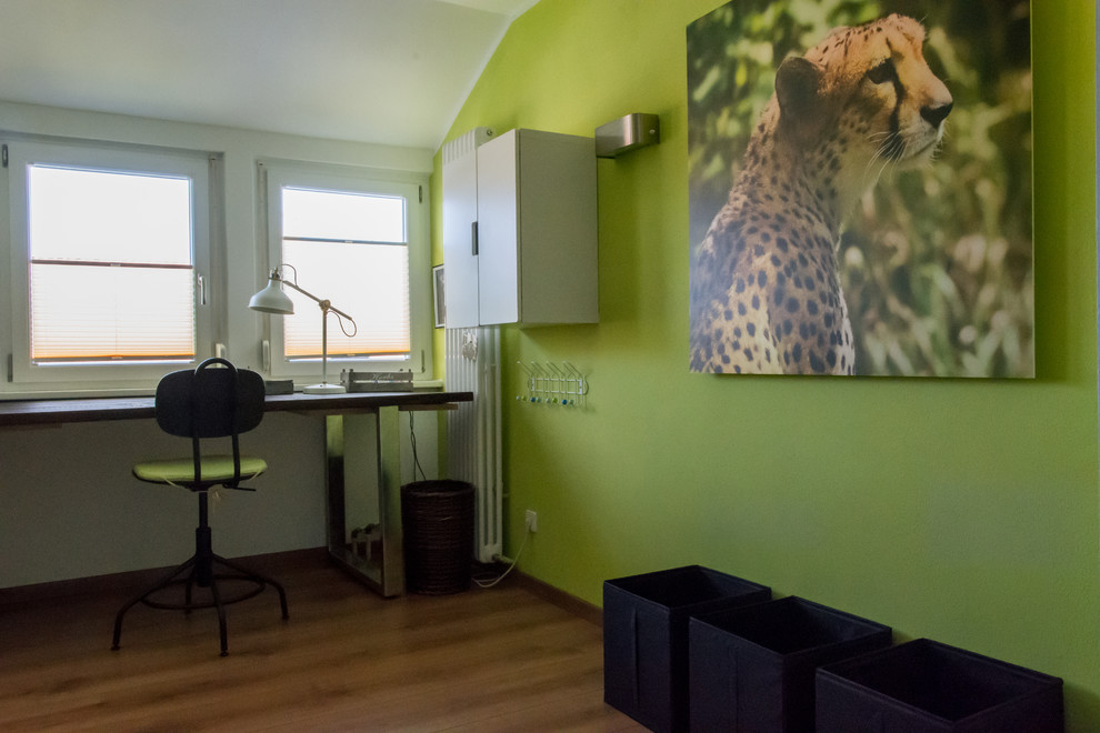 Photo of a mid-sized contemporary kids' bedroom for kids 4-10 years old and boys in Cologne with green walls, medium hardwood floors and brown floor.