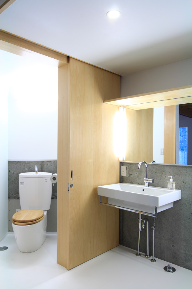 Photo of a contemporary powder room in London with a wall-mount sink, a one-piece toilet, gray tile, grey walls and linoleum floors.