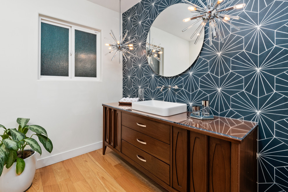 Huge 1960s blue tile and ceramic tile light wood floor and single-sink bathroom photo in San Diego with furniture-like cabinets, brown cabinets, a one-piece toilet, white walls, a vessel sink, glass countertops and a freestanding vanity