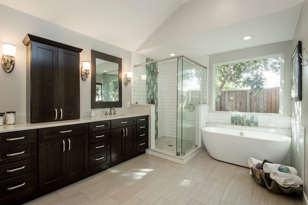 Design ideas for a mid-sized contemporary master bathroom in Los Angeles with shaker cabinets, dark wood cabinets, a curbless shower, a one-piece toilet, multi-coloured tile, porcelain tile, beige walls, plywood floors, an integrated sink, solid surface benchtops, beige floor, a sliding shower screen and white benchtops.