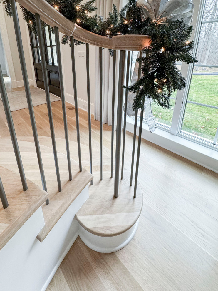 На фото: большая лестница на больцах в классическом стиле с деревянными ступенями, крашенными деревянными подступенками и перилами из смешанных материалов с