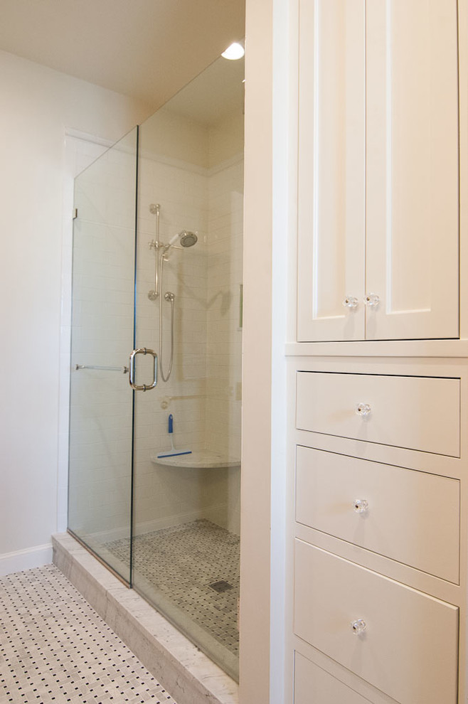 This is an example of a mid-sized transitional master bathroom in Portland Maine with an undermount sink, shaker cabinets, white cabinets, marble benchtops, a drop-in tub, an alcove shower, a two-piece toilet, white tile, mosaic tile, beige walls, mosaic tile floors, grey floor and a hinged shower door.