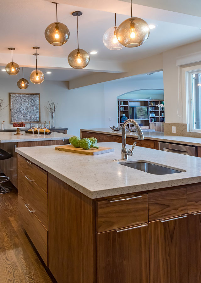 Photo of an expansive contemporary u-shaped eat-in kitchen in Los Angeles with flat-panel cabinets, medium wood cabinets, limestone benchtops, beige splashback, porcelain splashback, multiple islands, an undermount sink, stainless steel appliances, medium hardwood floors and brown floor.