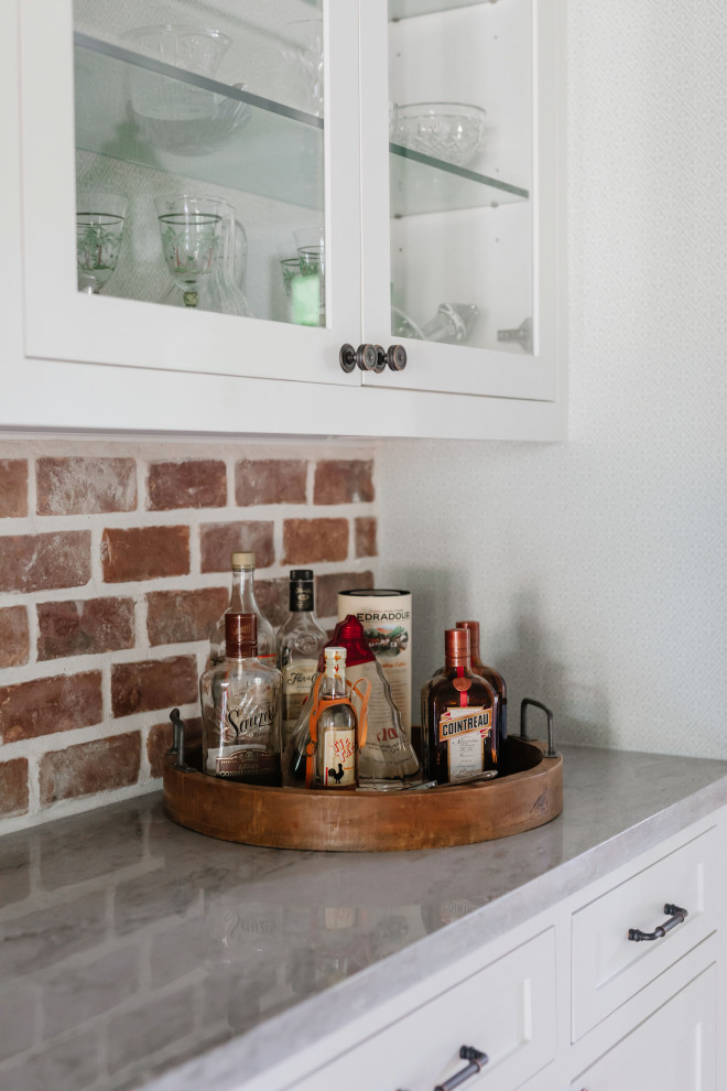 Design ideas for a small country single-wall home bar in Houston with shaker cabinets, white cabinets, quartzite benchtops, red splashback, brick splashback and grey benchtop.