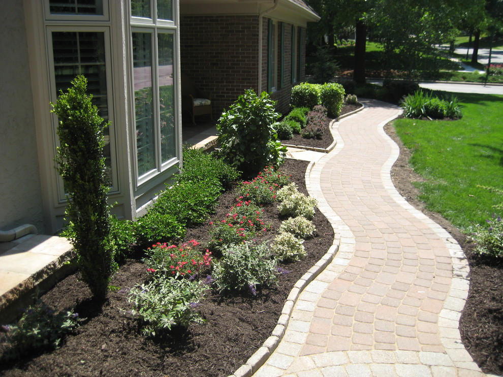 Photo of a mid-sized traditional front yard full sun formal garden in Kansas City with concrete pavers.