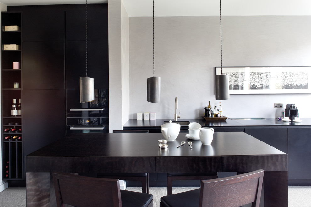 Contemporary kitchen in London with flat-panel cabinets, black cabinets, with island, an undermount sink and black appliances.