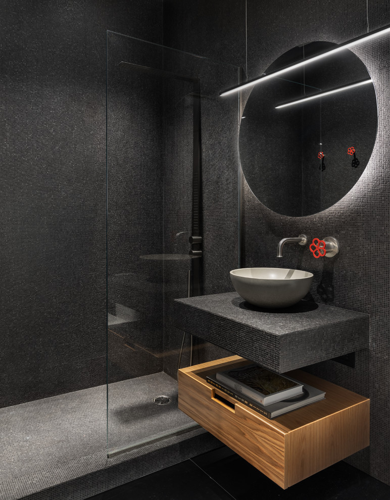 Mid-sized contemporary 3/4 bathroom in New York with flat-panel cabinets, medium wood cabinets, black tile, mosaic tile, slate floors, a vessel sink, black floor, an open shower, black benchtops, an alcove shower, tile benchtops and black walls.