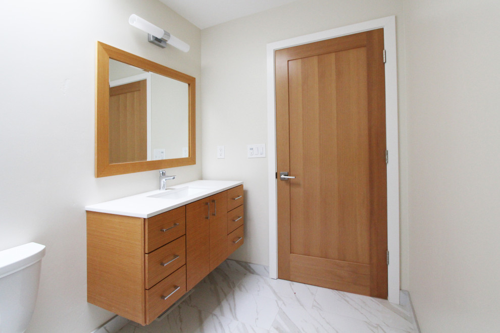Mid-sized transitional 3/4 black and white tile and porcelain tile porcelain tile, white floor and single-sink alcove bathtub photo with flat-panel cabinets, light wood cabinets, a two-piece toilet, white walls, an undermount sink, quartz countertops, white countertops, a niche and a floating vanity
