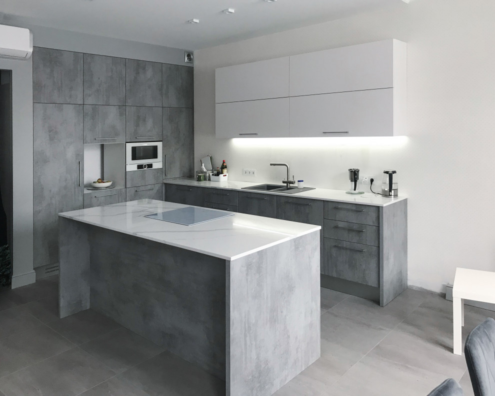 Moderne Küche in grau-weiß in L-Form mit flächenbündigen Schrankfronten, grauen Schränken, Küchenrückwand in Weiß, Küchengeräten aus Edelstahl, Kücheninsel, grauem Boden, weißer Arbeitsplatte und Kassettendecke in Sonstige
