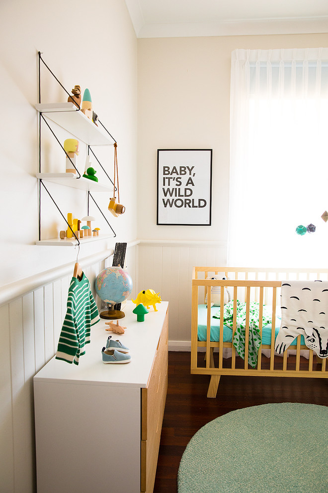 This is an example of a contemporary gender-neutral nursery in Other with beige walls, dark hardwood floors and brown floor.