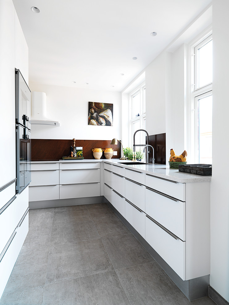 This is an example of a mid-sized contemporary l-shaped separate kitchen in Copenhagen with flat-panel cabinets, white cabinets, brown splashback, no island, a double-bowl sink, granite benchtops, stainless steel appliances and limestone floors.