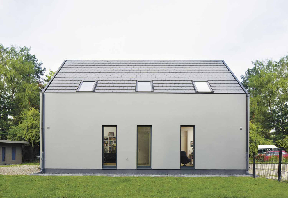 Diseño de fachada de casa gris y negra minimalista de tamaño medio a niveles con revestimiento de estuco y tejado de teja de barro