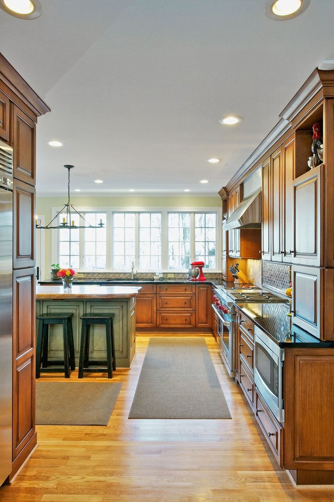 Inspiration for a mid-sized rustic l-shaped medium tone wood floor and brown floor open concept kitchen remodel in Orange County with an undermount sink, raised-panel cabinets, medium tone wood cabinets, granite countertops, beige backsplash, ceramic backsplash, stainless steel appliances and an island