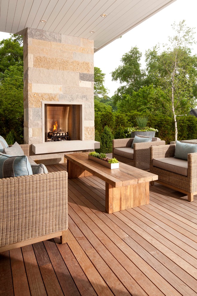 Photo of a large transitional backyard deck in Minneapolis with a fire feature and a roof extension.