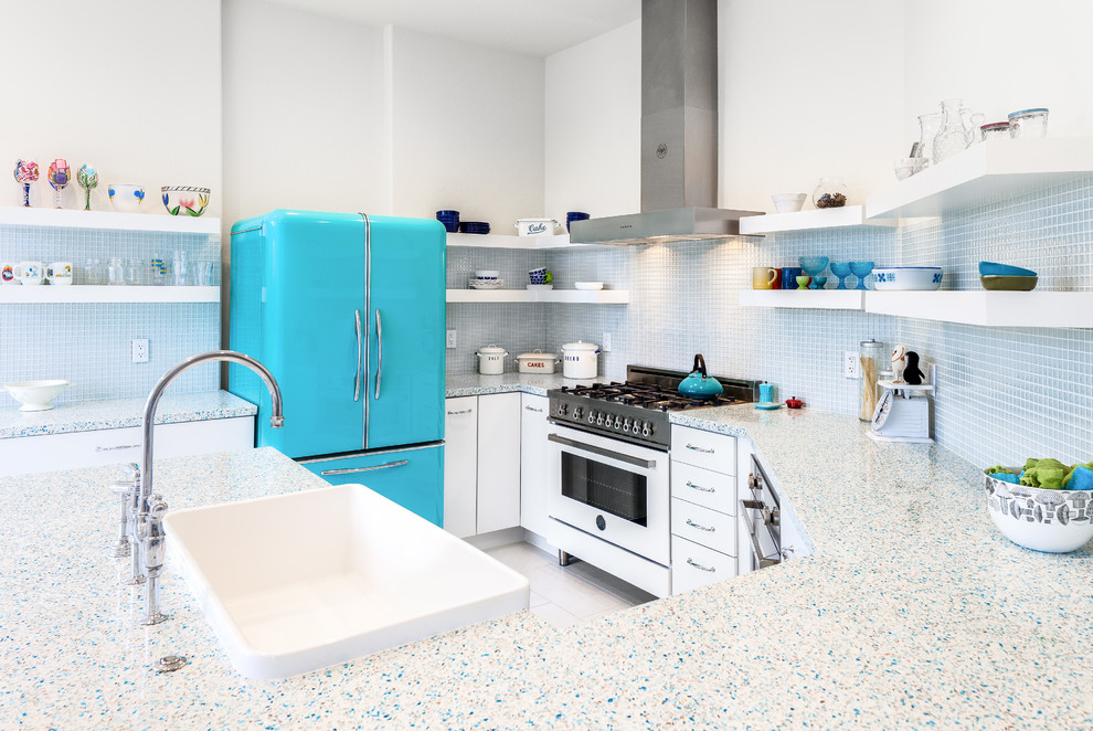 Photo of a small eclectic u-shaped eat-in kitchen in San Francisco with a farmhouse sink, flat-panel cabinets, white cabinets, recycled glass benchtops, blue splashback, glass sheet splashback and porcelain floors.