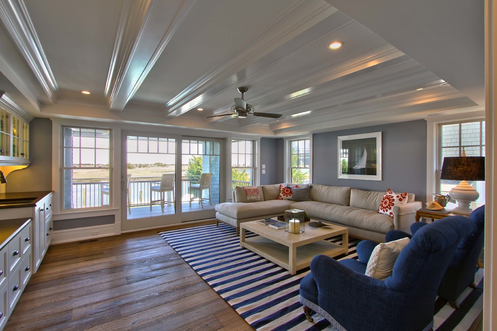 This is an example of a large beach style enclosed family room in Philadelphia with a home bar, grey walls, medium hardwood floors, a wall-mounted tv, no fireplace and brown floor.