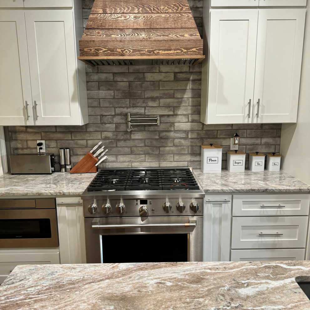 Inspiration for a transitional galley medium tone wood floor and brown floor eat-in kitchen remodel in Atlanta with an undermount sink, shaker cabinets, white cabinets, granite countertops, gray backsplash, ceramic backsplash, stainless steel appliances, an island and multicolored countertops